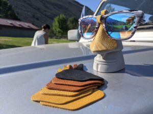 Leather Nose Cones laid out on the hood of a car, a fully assembled sunglasses and nose cone are fit on a easter island shaped face with a large life size nose.